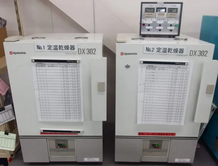 定温乾燥器（DX302）で電子部品のベーキング処理を行い含水を除去する工程