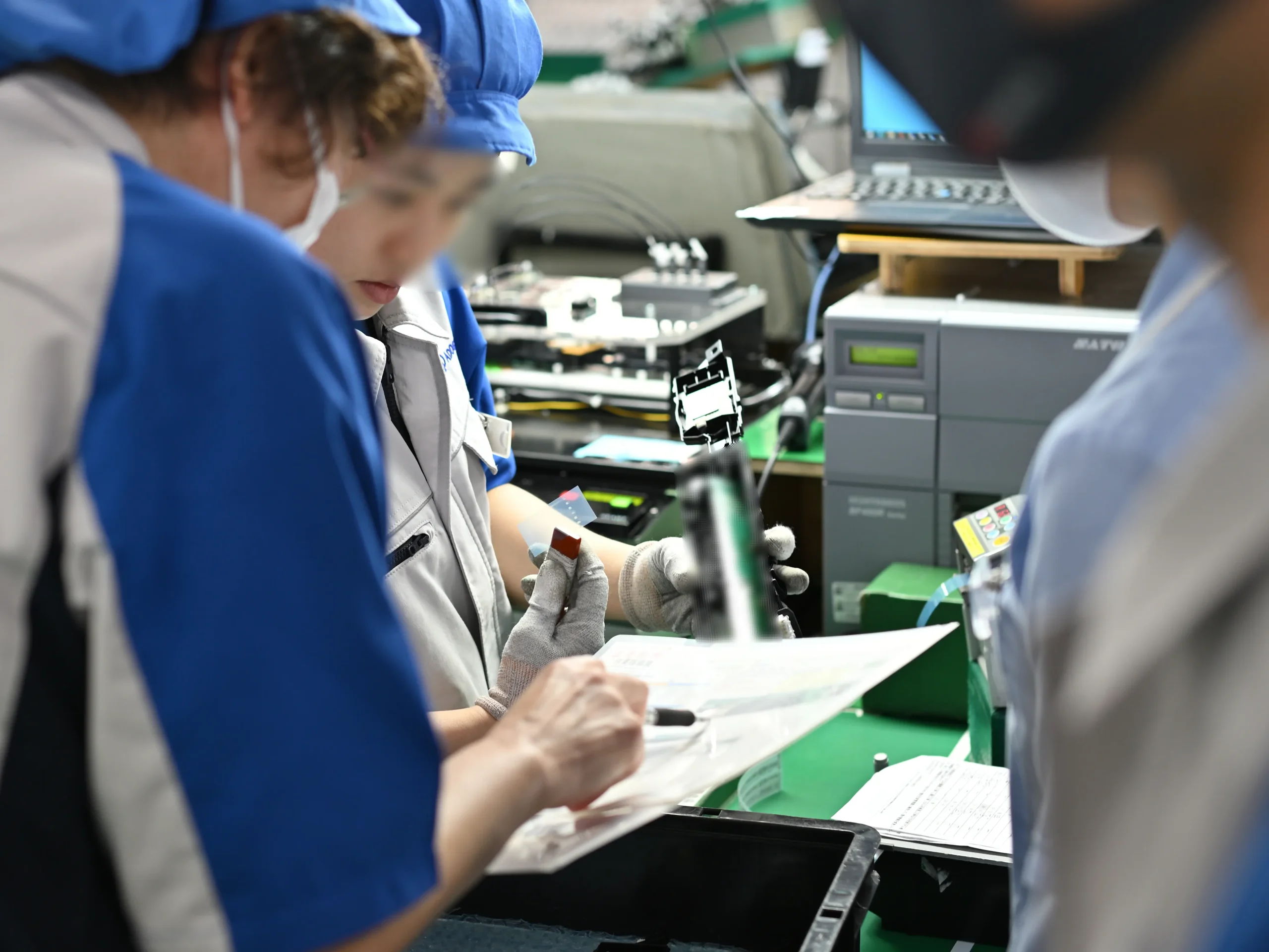 作業現場で複数の担当者が文書を確認しながら、品質システムの内部監査を協働で進めている様子