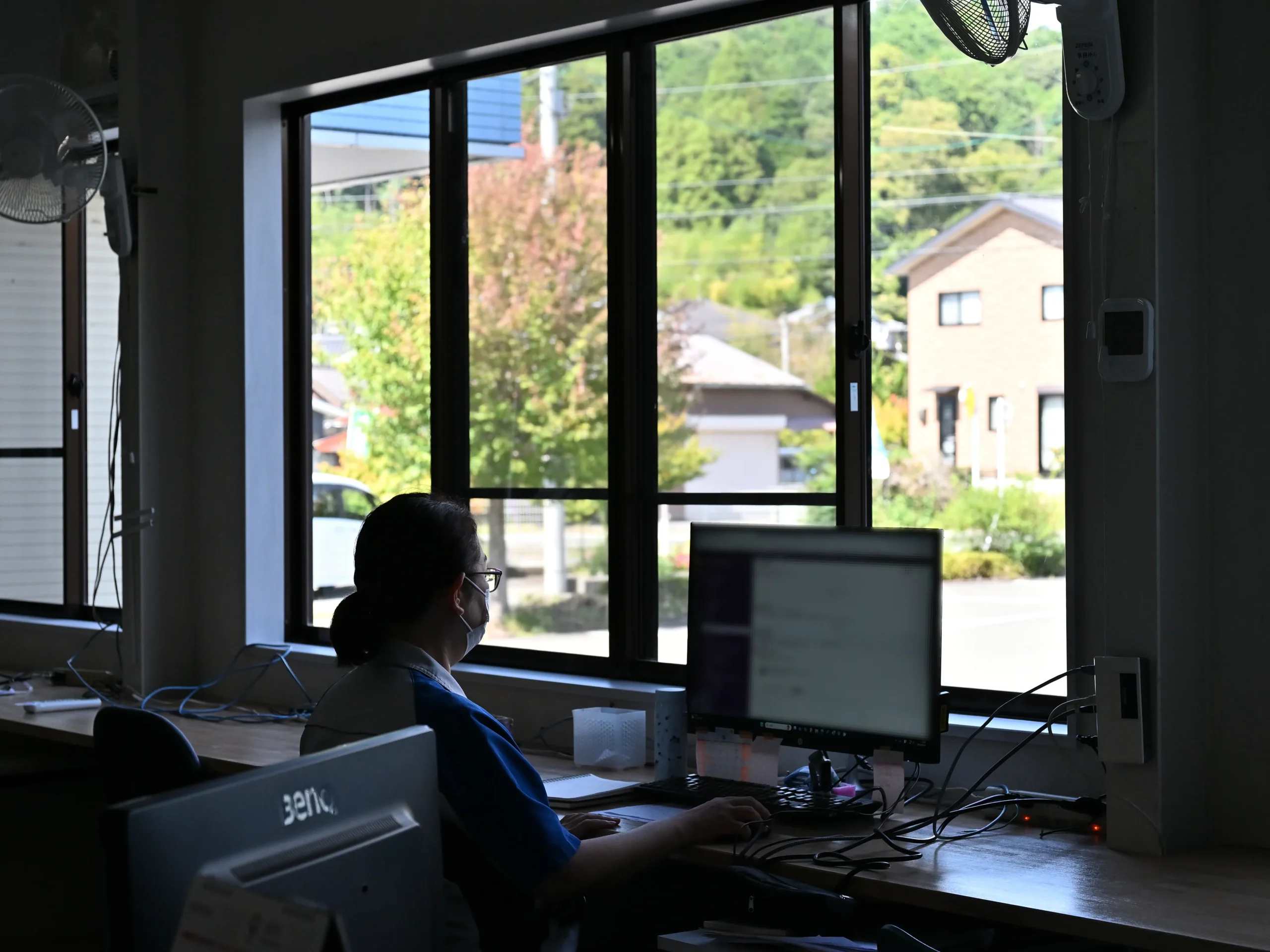 事務所窓際の席で仕事に集中する従業員。窓からは、季節の移り変わりが望める。