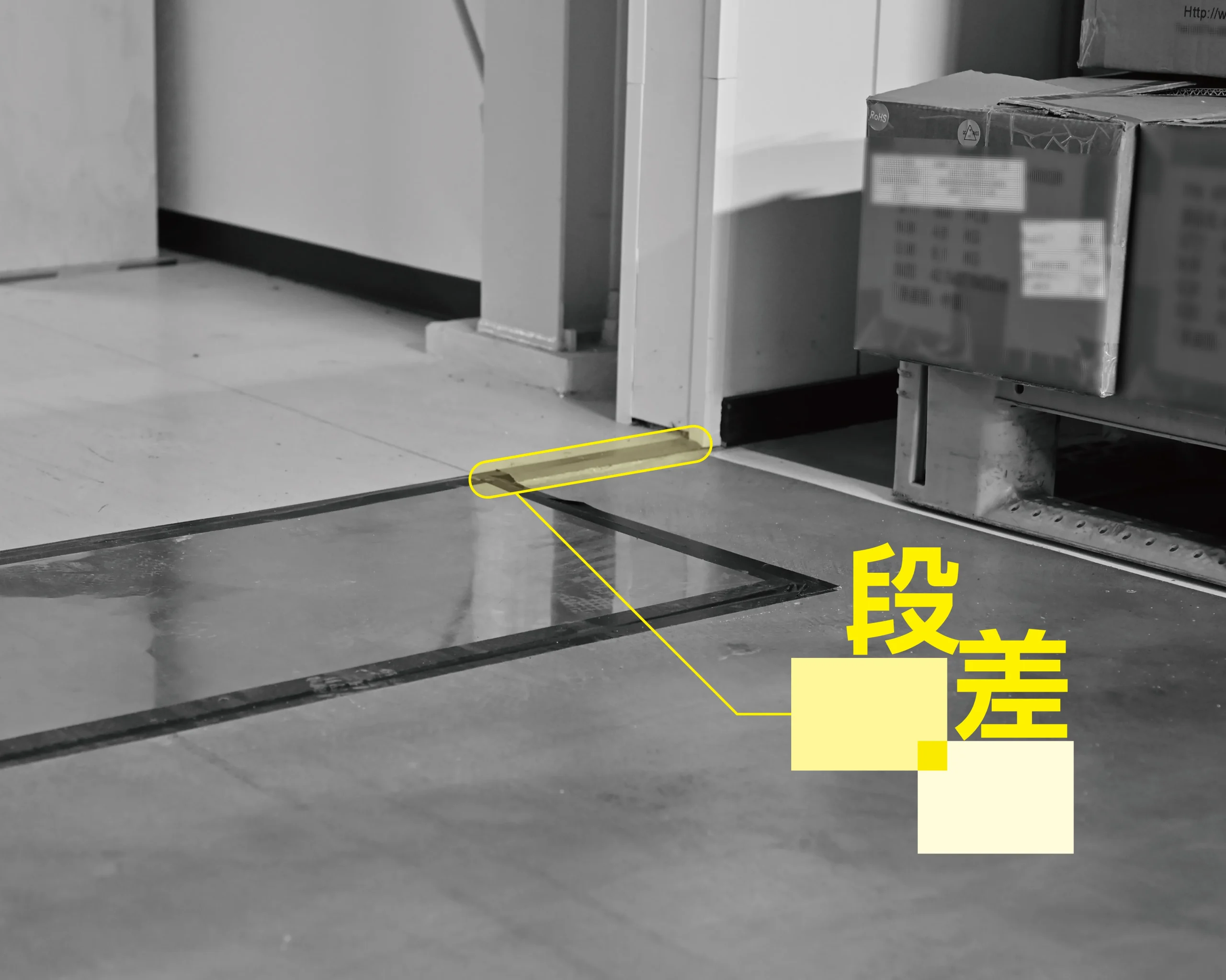 製造現場の通路にある段差と鉄板による転倒防止対策の様子。