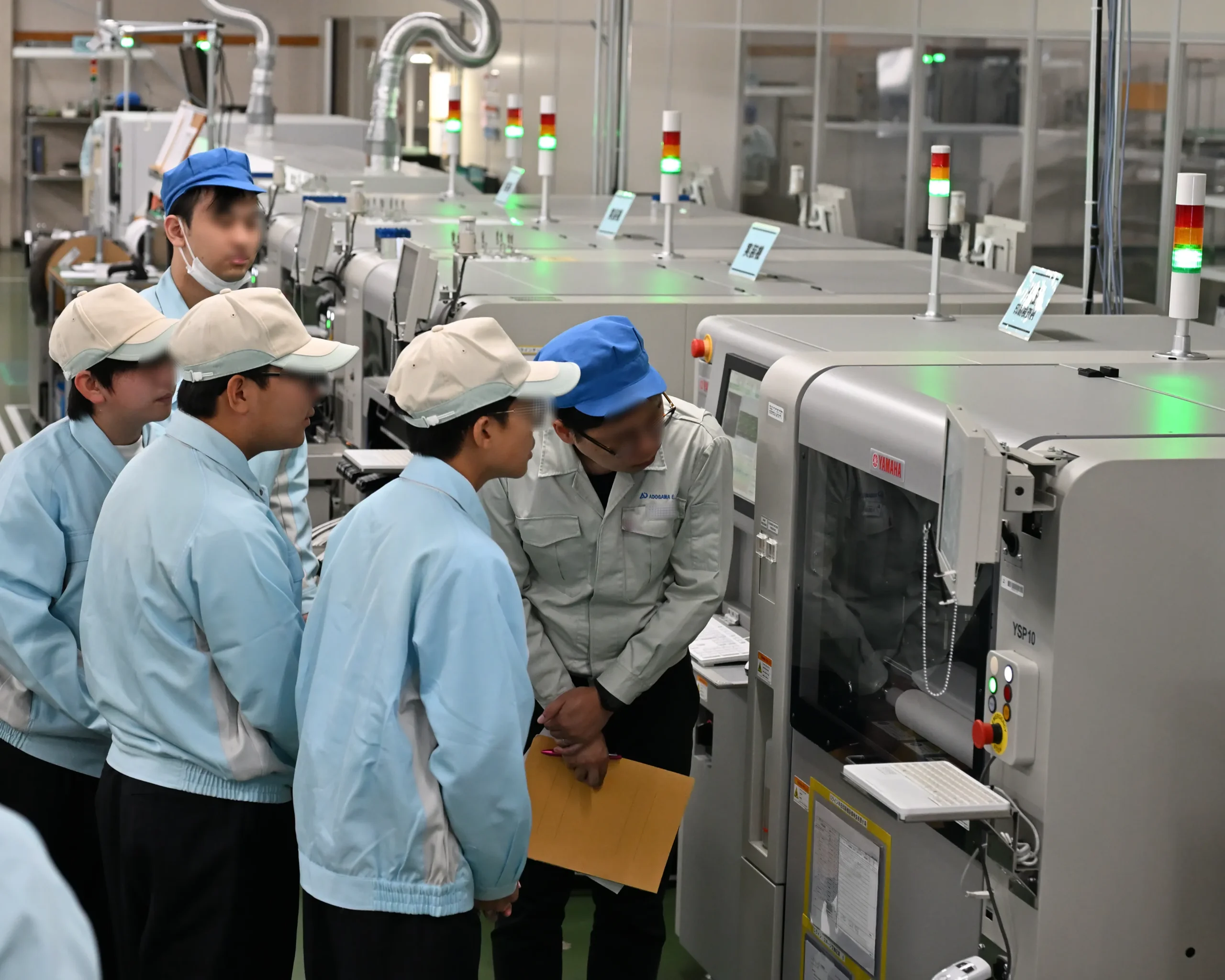 プリント基板に電子部品が実装される様子を見学する安曇川中学生。