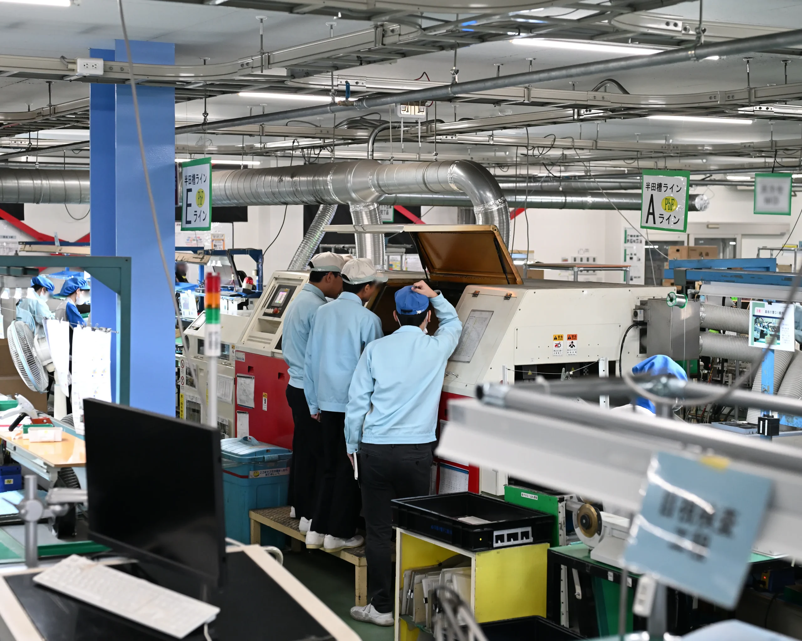 職場体験初日にアドガワエレクトロニクスのフローはんだ槽、ライン作業を見学して、基板実装の全体像を把握する安曇川中学生たち。