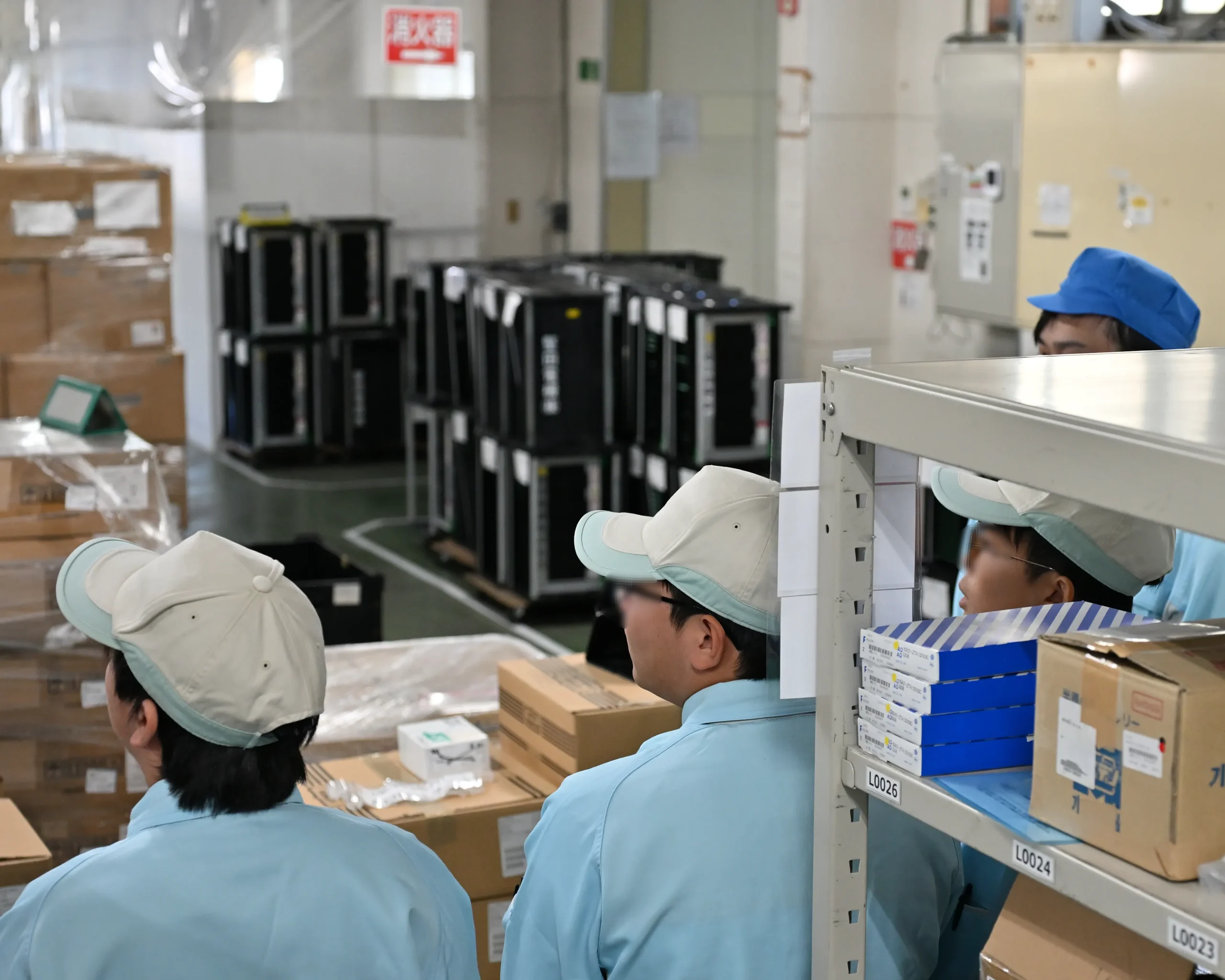 工程ごとに異なる作業と労働環境を、資材保管倉庫で説明するアドガワエレクトロニクス従業員。