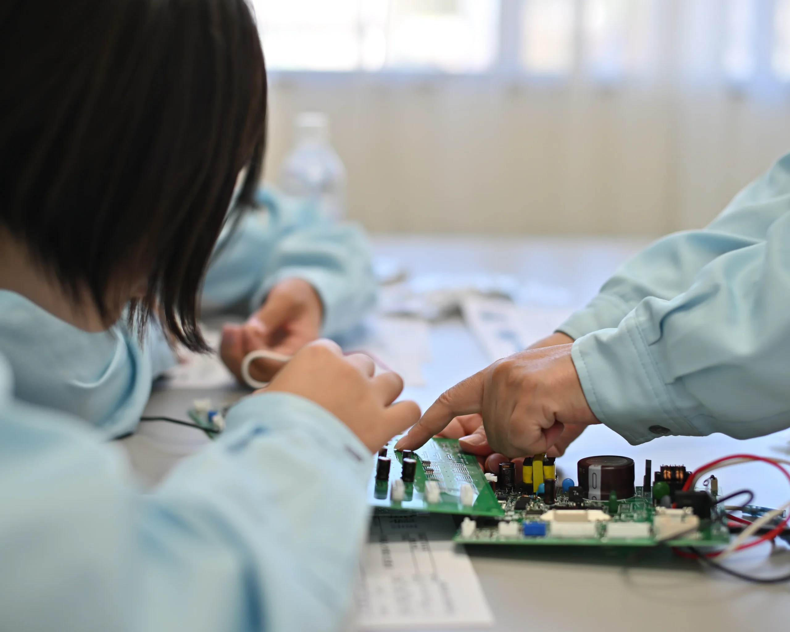 安曇川中学校のチャレンジウィークで、品質管理部からプリント基板の表面実装技術について説明を聞く生徒