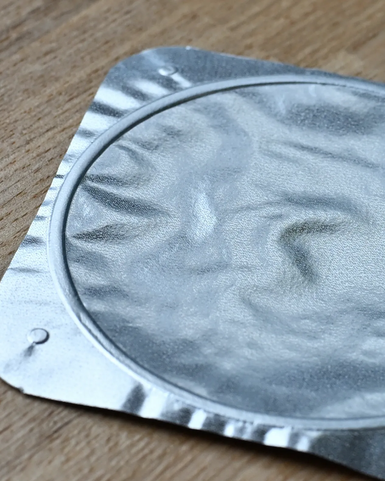 ヨーグルトのフタ。フタには目視でもわずかな凹凸が見え、指を滑らすとざらっとした感覚が残る。このザラつきが、ヨーグルトがフタにつかない秘密。