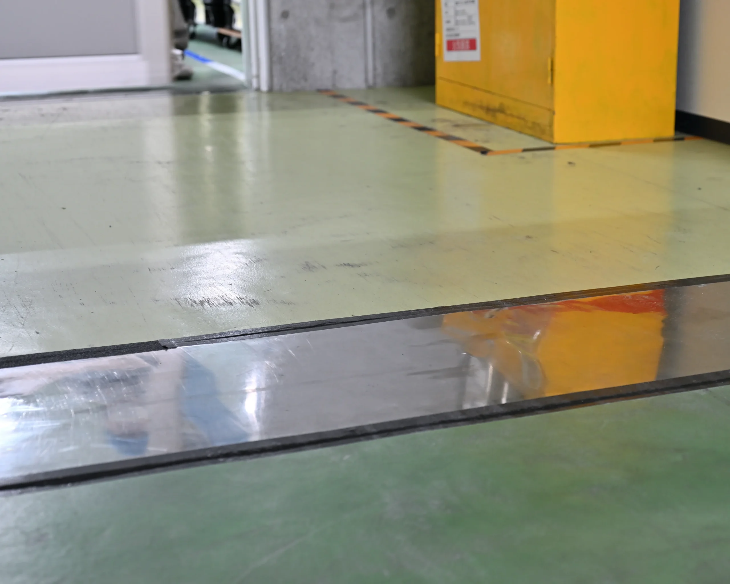 製造現場の通路に新たに設置された幅広の鉄板と滑り止めテープによる安全対策。